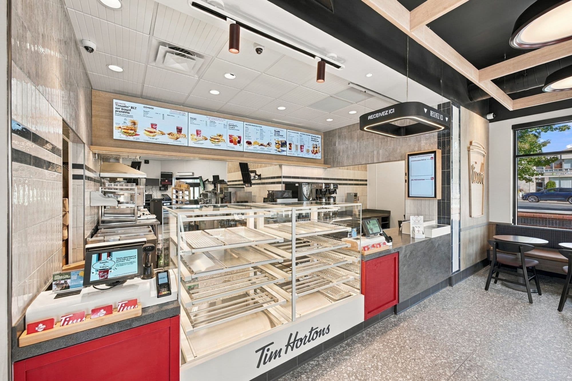 Vue en angle du comptoir de commande, de la vitrine de beignes et des écrans de menu