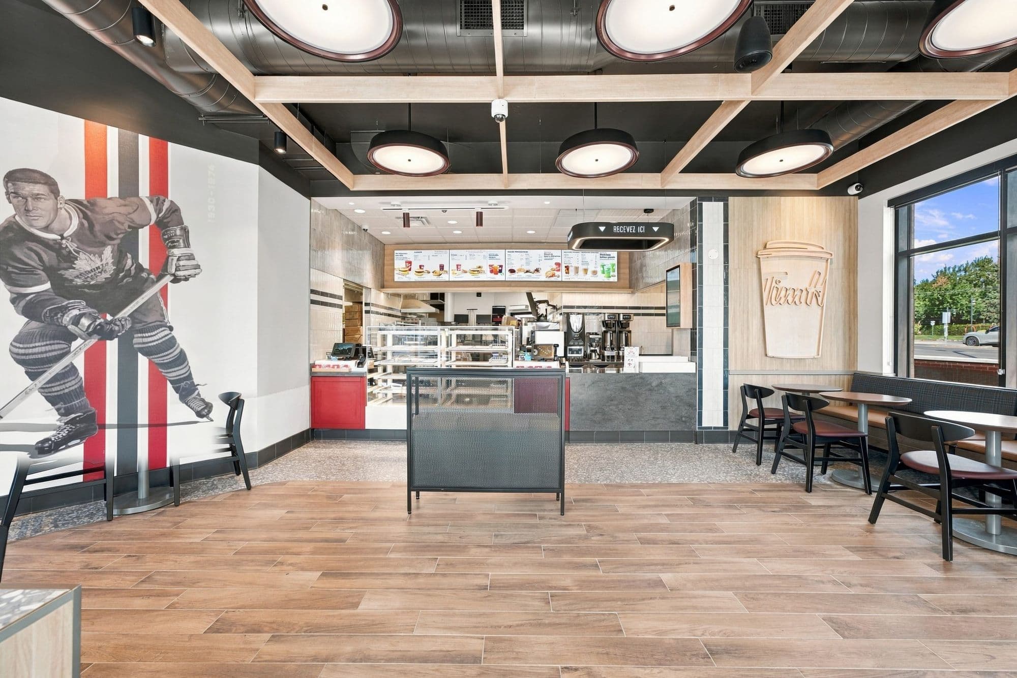 Salle à manger avec murale de hockeyeur, plafond à poutres de bois et plancher de bois