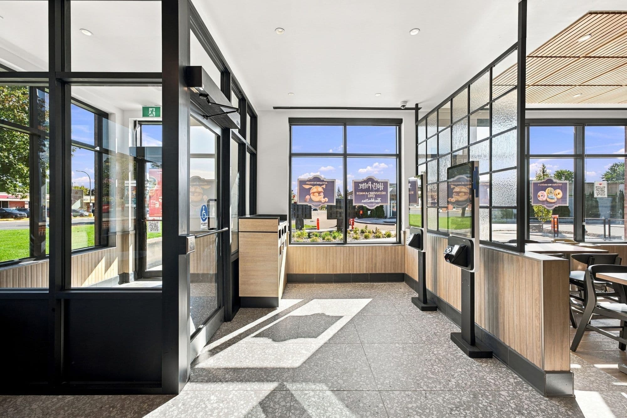 Vestibule d’entrée vitré et bornes de commande, avec vue sur l’extérieur