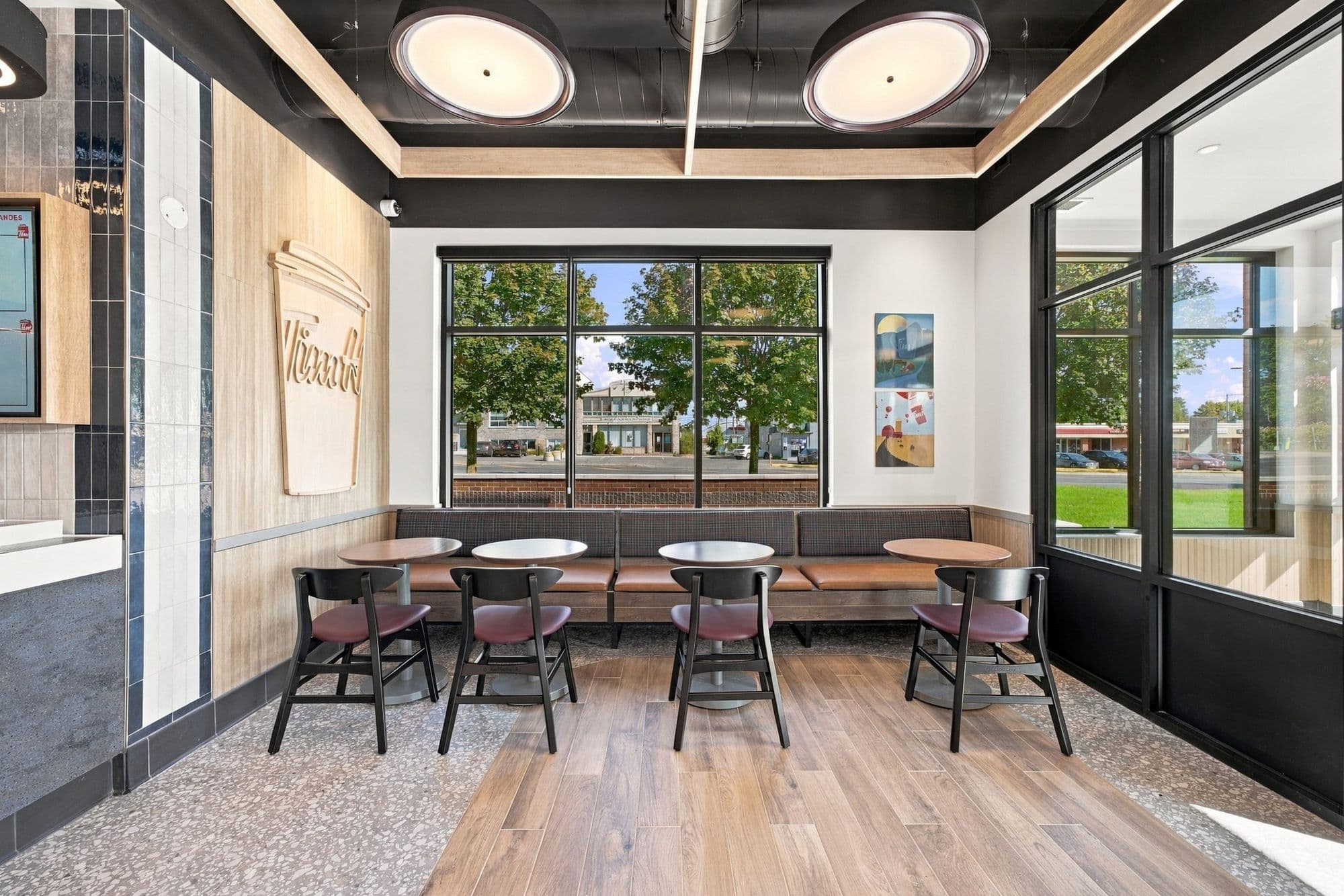 Banquette et tables de la salle à manger devant une grande fenêtre
