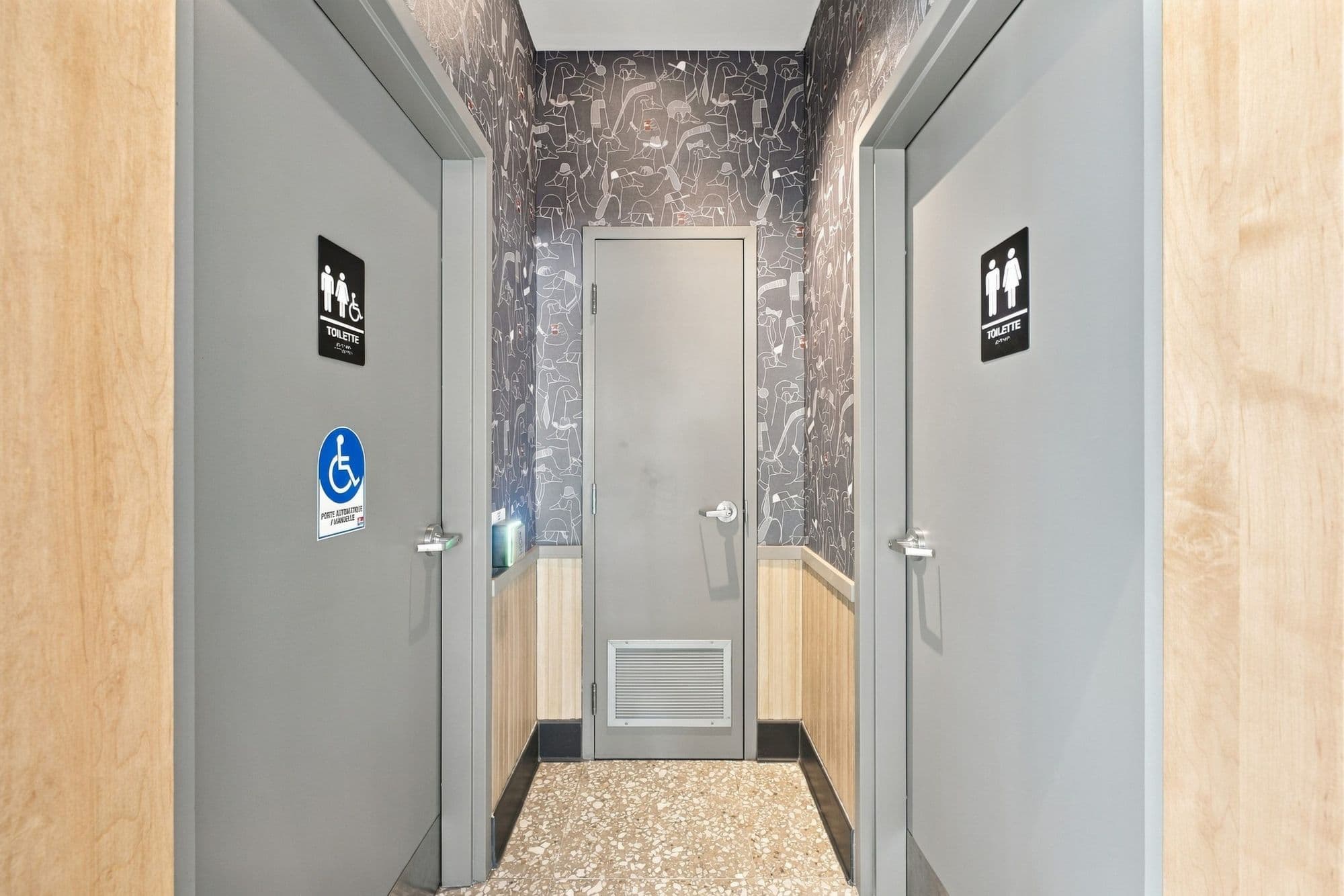 Corridor menant aux toilettes, avec signalisation de l’accessibilité