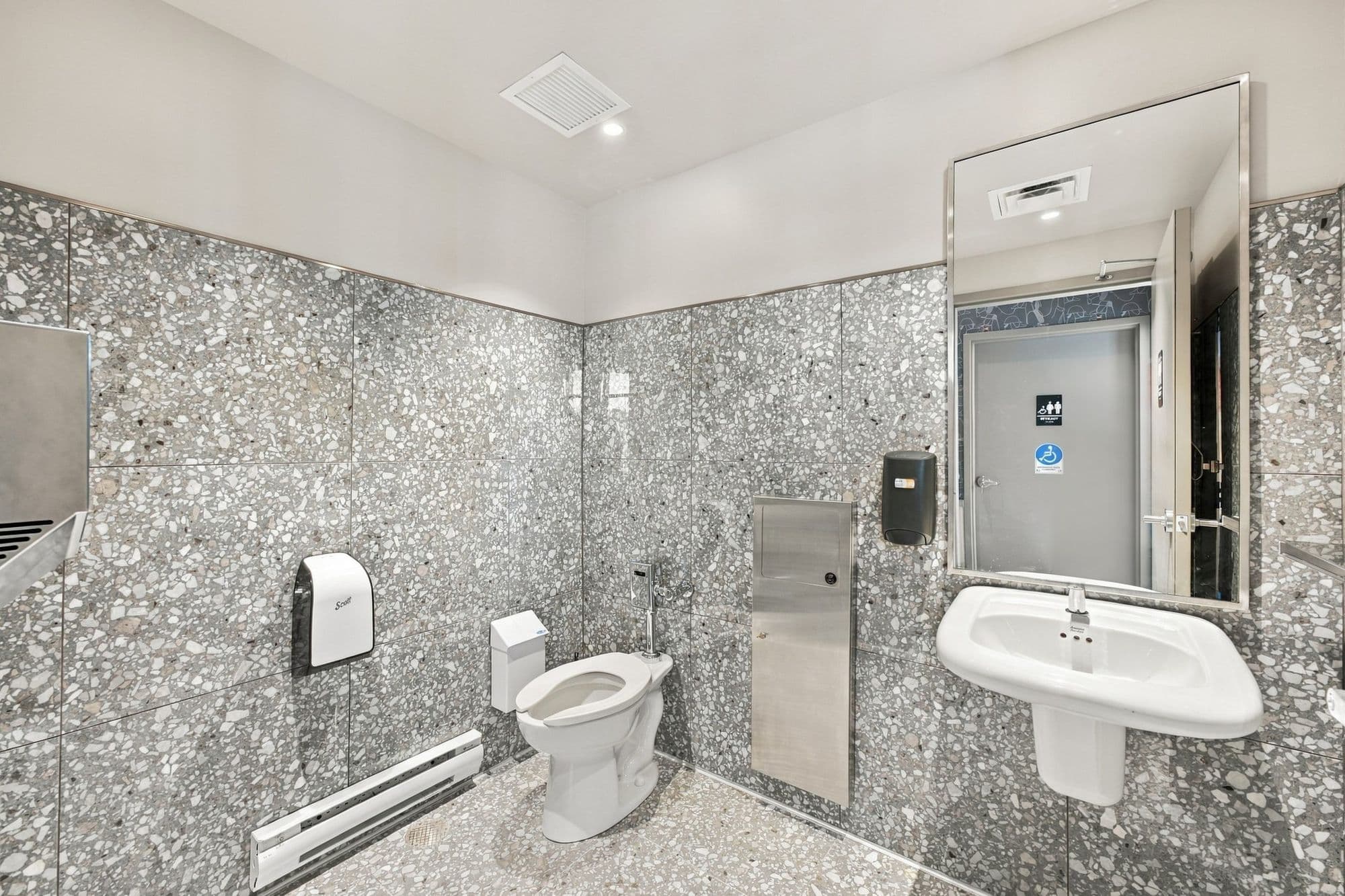 Toilette accessible avec revêtement de terrazzo au mur et au sol