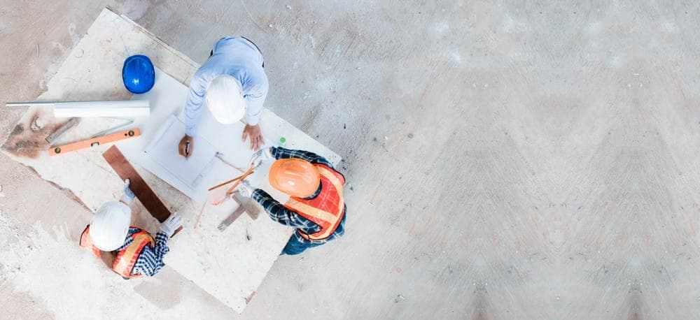 Vue de haut de travailleurs de la construction penchés sur des plans