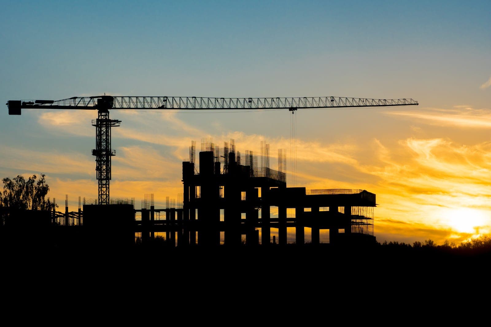 Silhouette d’une grue et d’un bâtiment en construction au coucher du soleil