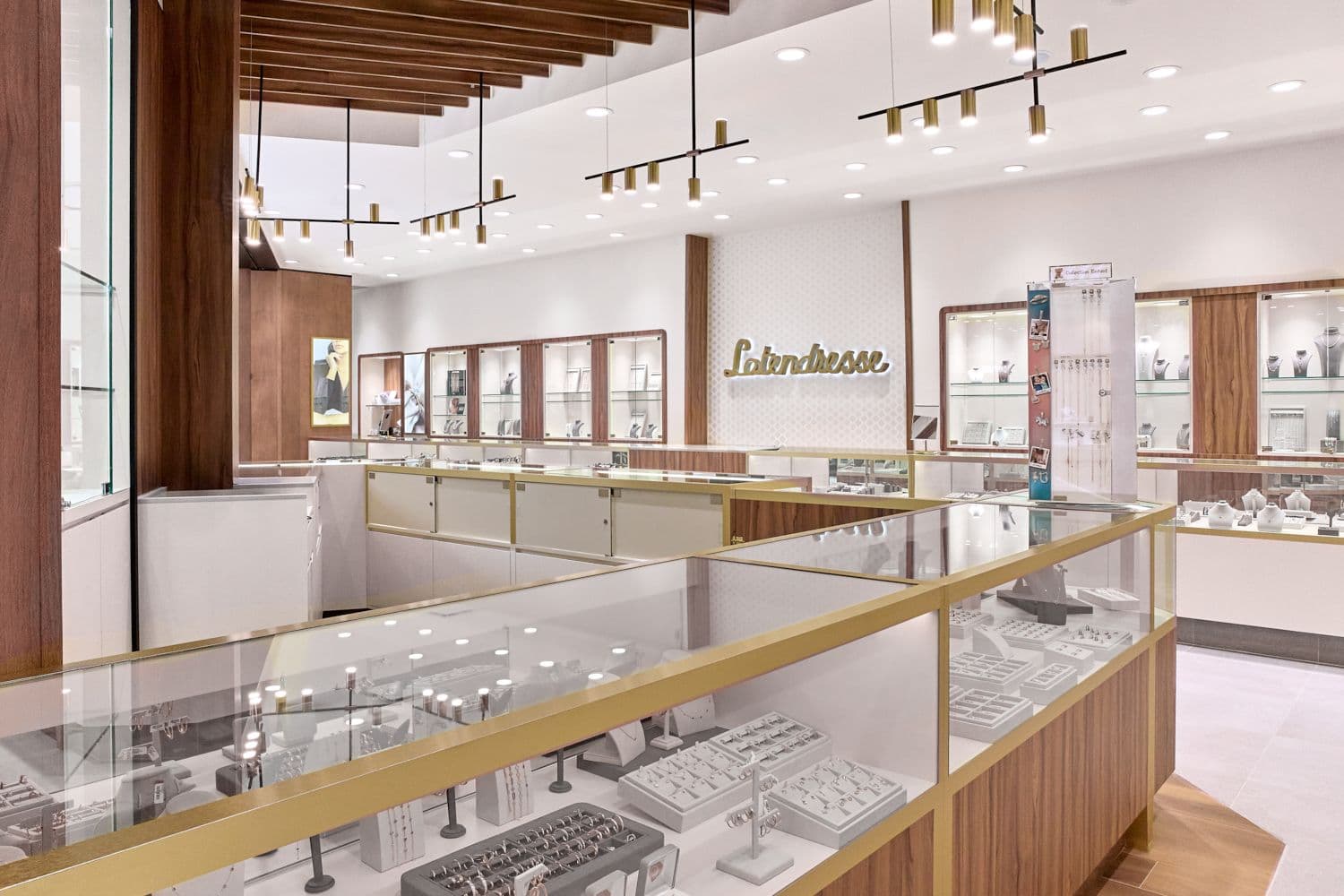 Comptoirs vitrés à bordure dorée sous un plafond de lattes de bois et des luminaires suspendus