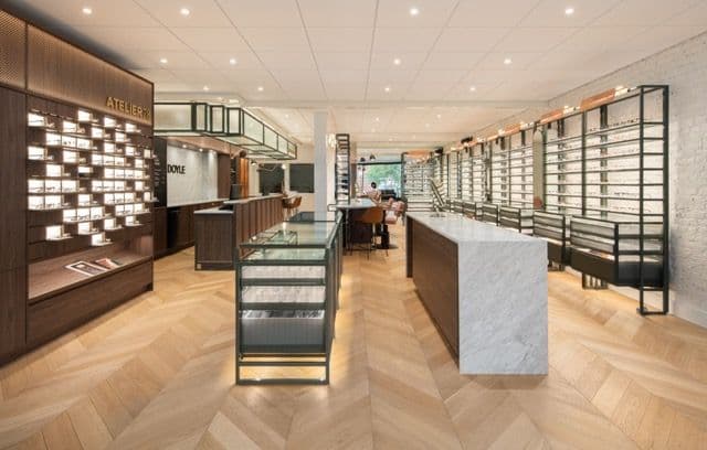 Allée centrale avec murs de présentation en bois, îlot en marbre et plancher à chevrons