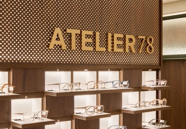 Enseigne « Atelier 78 » en lettres dorées au-dessus de tablettes de lunettes éclairées