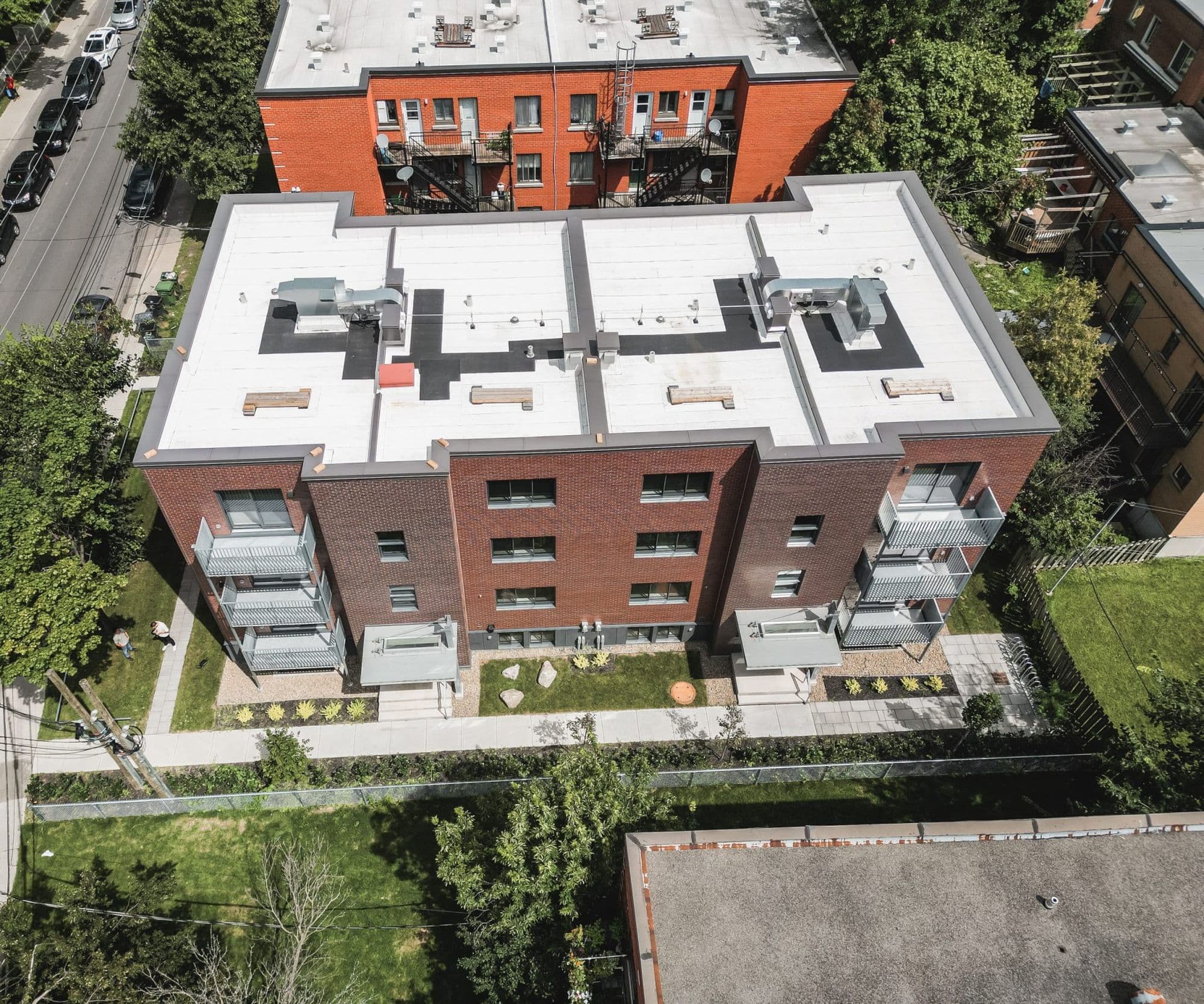 Vue aérienne de l’immeuble Barclay rénové, avec toit blanc, balcons neufs et cour aménagée